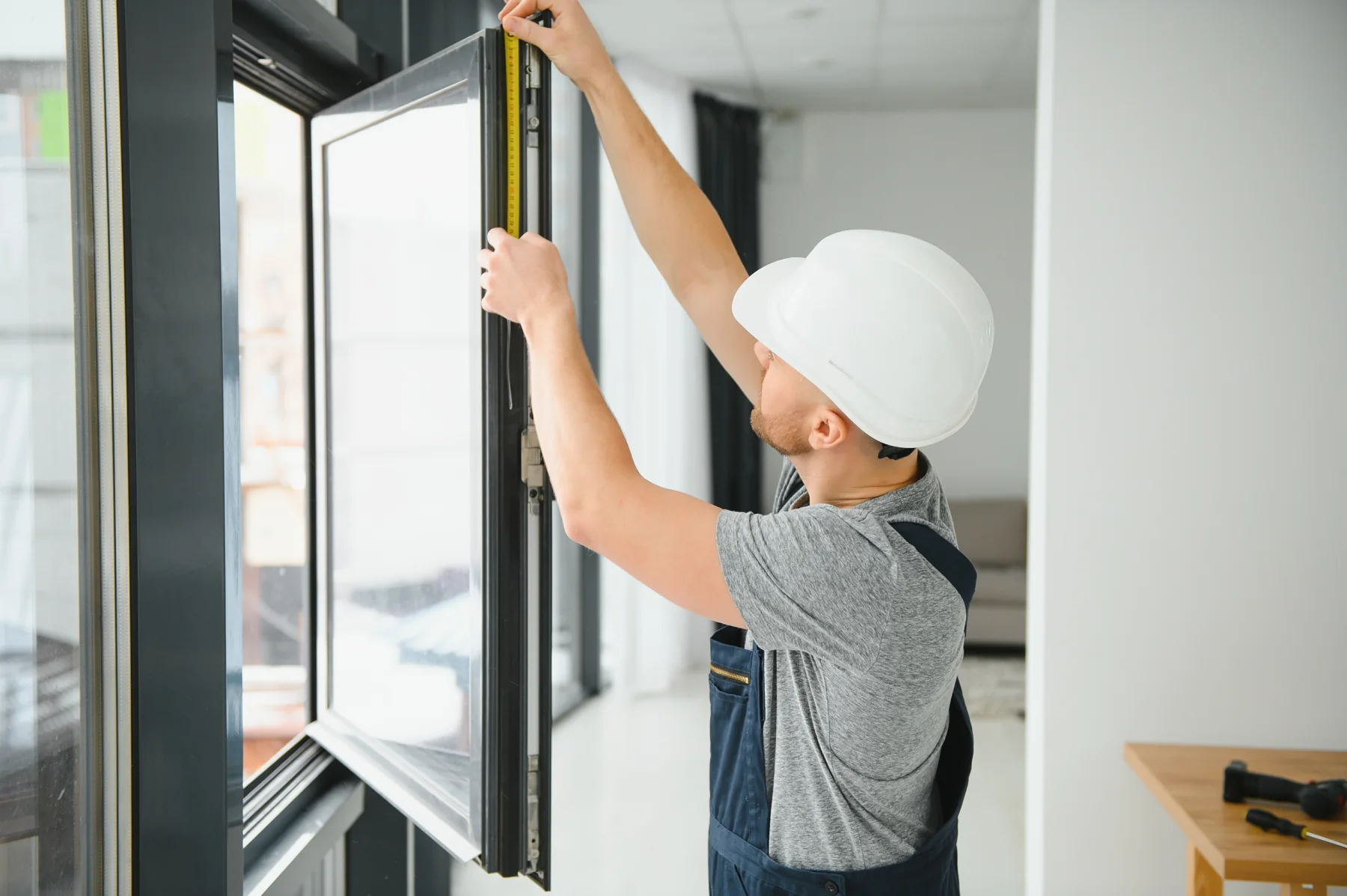 Fenstermonteur misst einen geöffneten Fensterrahmen