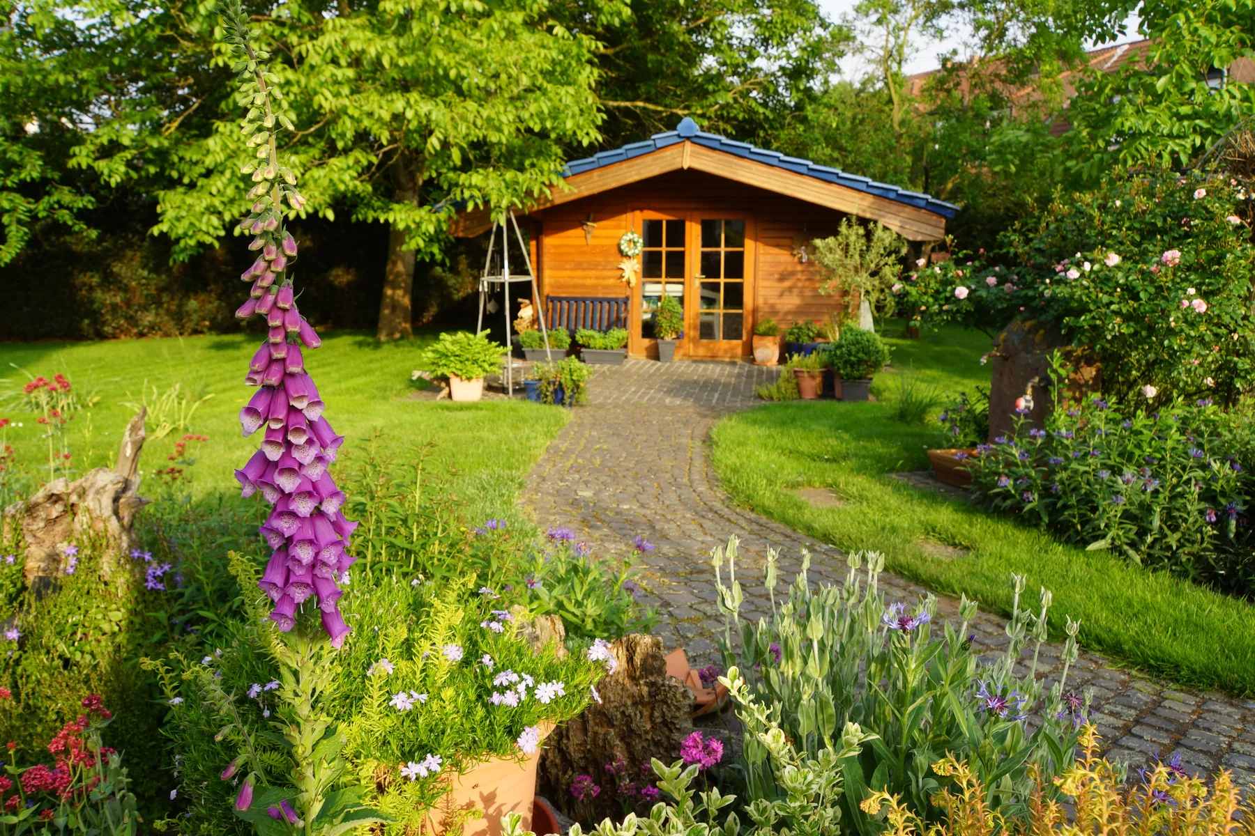 Gartenhaus im Garten Holzgartenhaus zwischen Bäumen und Blumen im Garten