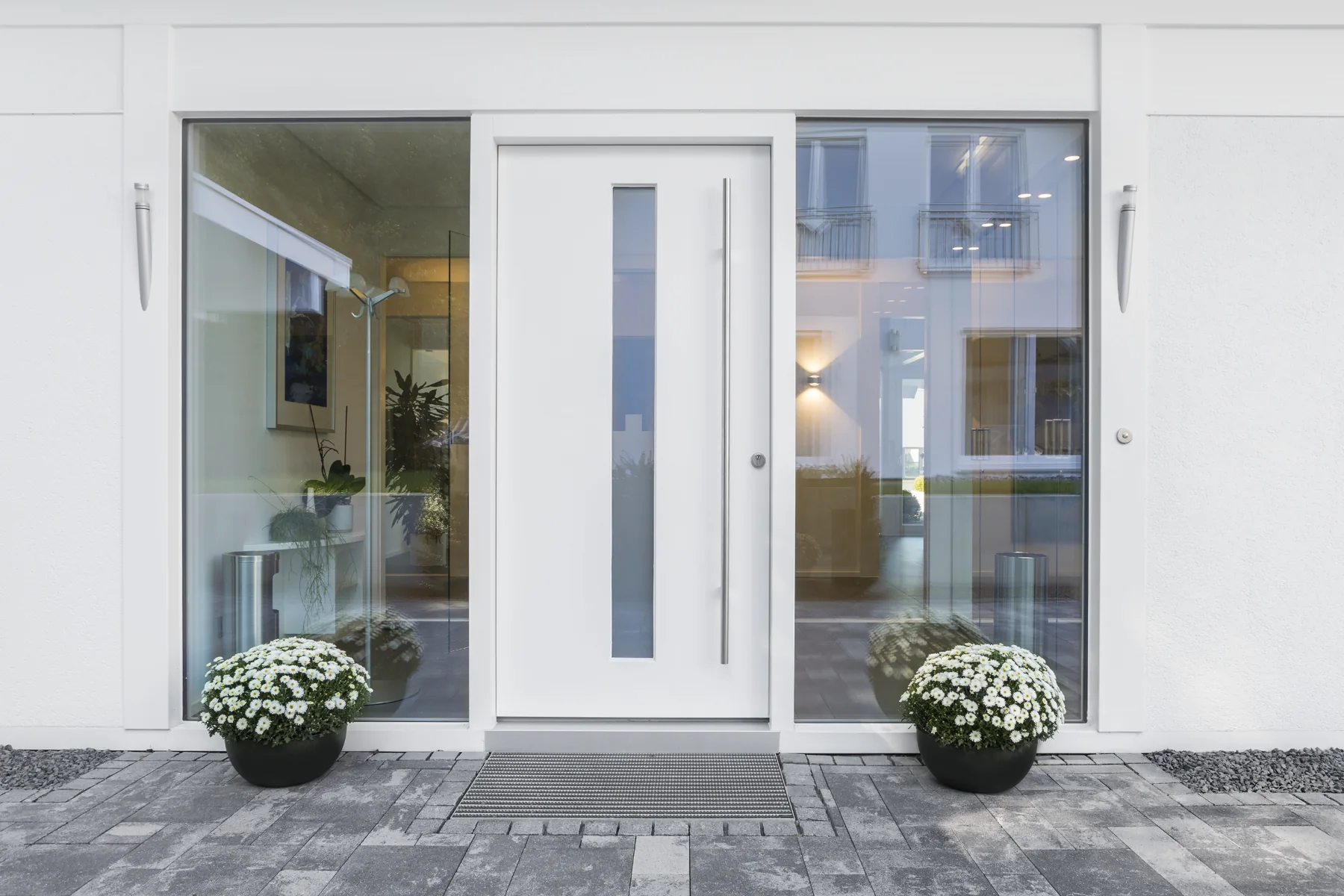 Moderne weiße Haustür mit verglasten Seitenteilen an einem Wohnhaus