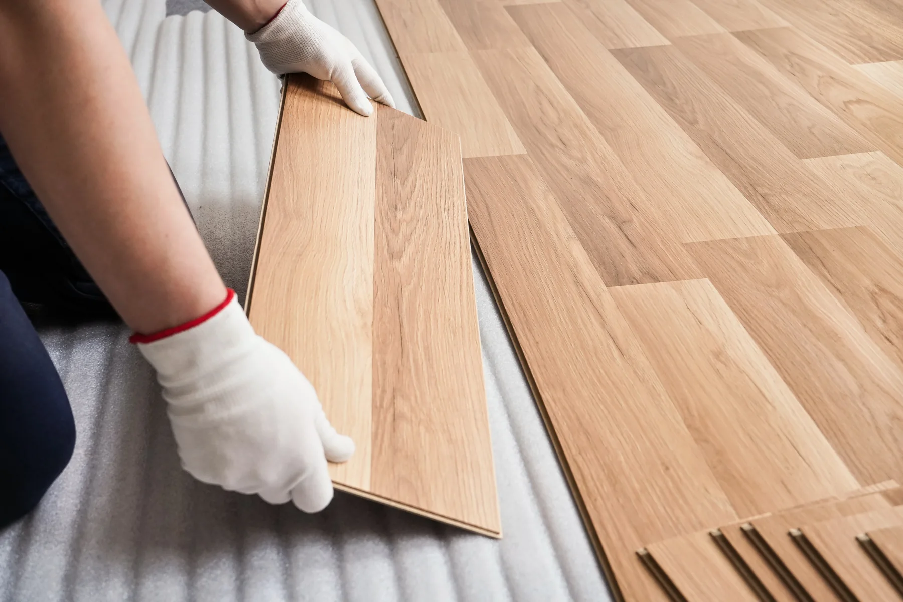 Handwerker verlegt Holzoptik-Boden in einem Wohnraum