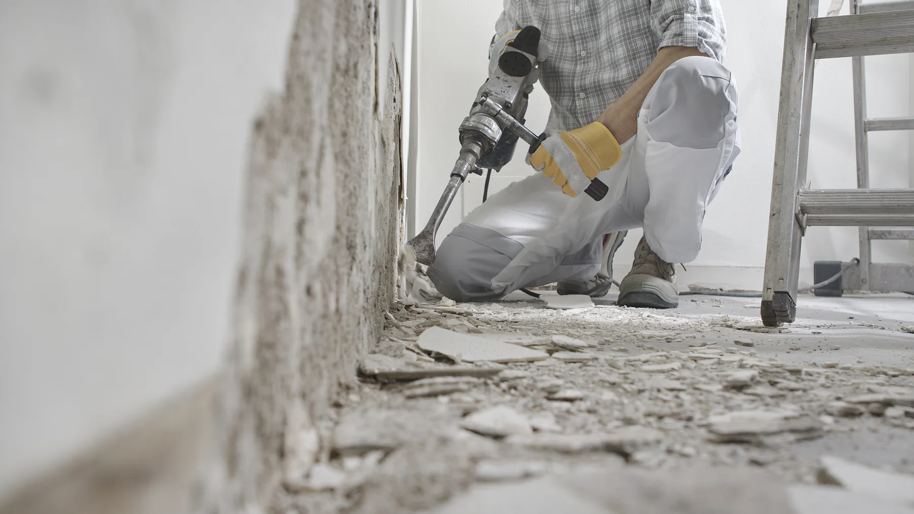 Handwerker entfernt alte Bodenschichten bei einer Renovierung