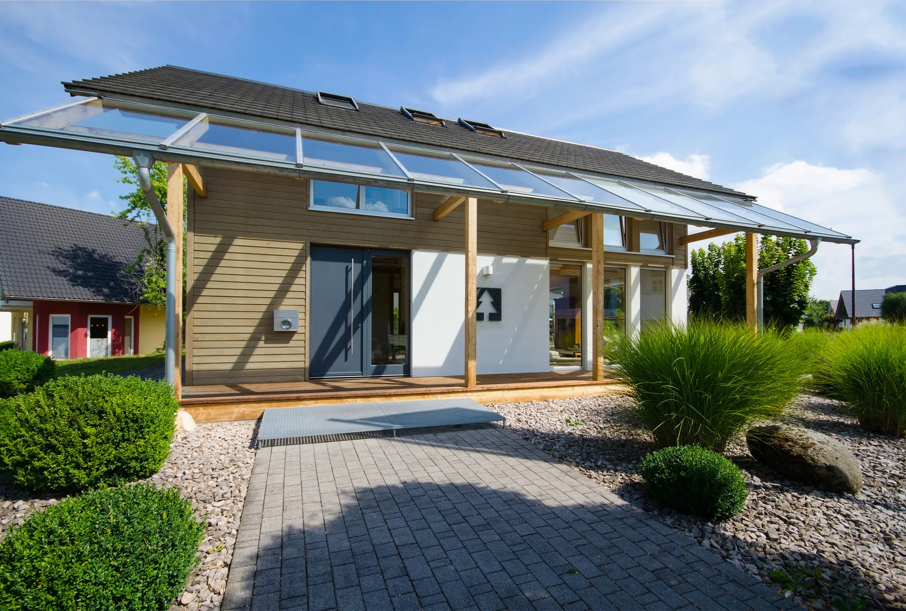 Terrassenüberdachung am hellen Wohnhaus Helle Terrassenüberdachung vor einem Wohnhaus mit angrenzendem Garten