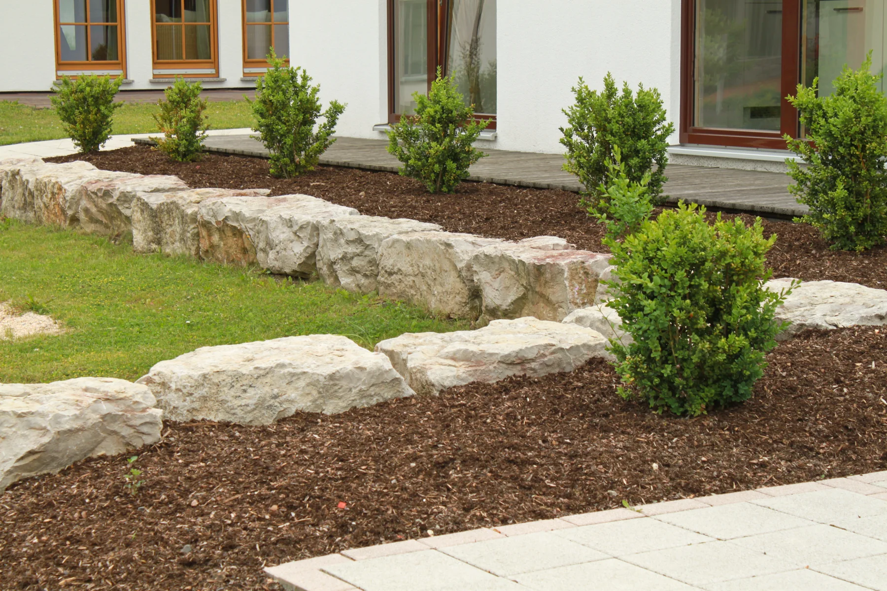 Niedrige Natursteinmauer als Einfassung eines bepflanzten Beets